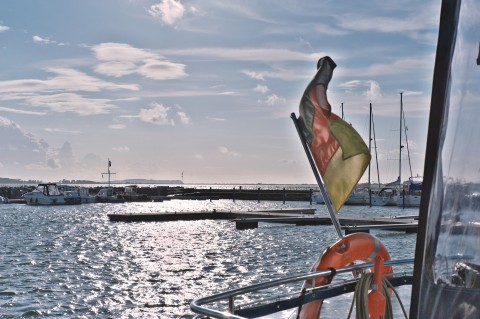 Bild: Beflaggt - Im Hafen von Wiek auf der Insel Rügen. Im Hintergrund des Fotos ist der Dornbusch von Hiddensee mit dem Leuchtturm zu sehen. NIKON D700 mit TAMRON SP 24-70mm F/2.8 Di VC USD. ISO 200 ¦ f/9 ¦ 50 mm ¦ 1/6400 s ¦ kein Blitz. Klicken Sie auf das Bild um es zu vergrößern.