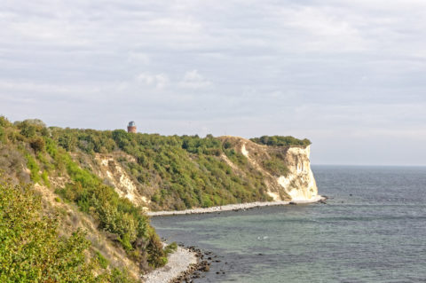 Bild: Blick vom Hochuferweg vom Fischerdorf Vitt zum Kap Arkona. Der alte Marinepeilturm des Jahres 1927 ist gut zu erkennen. Er diente zur Verbesserung der Sicherheit des Fährverkehrs auf der Königslinie zwischen Sassnitz und Trelleborg. Seine technischen Einrichtungen wurden 1945 nach dem Zweiten Weltkrieg zerstört. Klicken Sie auf das Bild um es zu vergrößern.